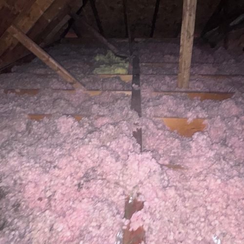 Old dirty fiberglass insulation removal in residential attic Georgia.