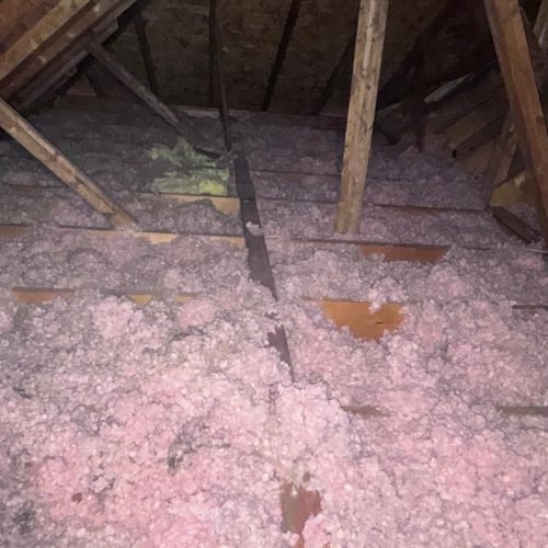 Old dirty fiberglass insulation removal in residential attic Georgia.