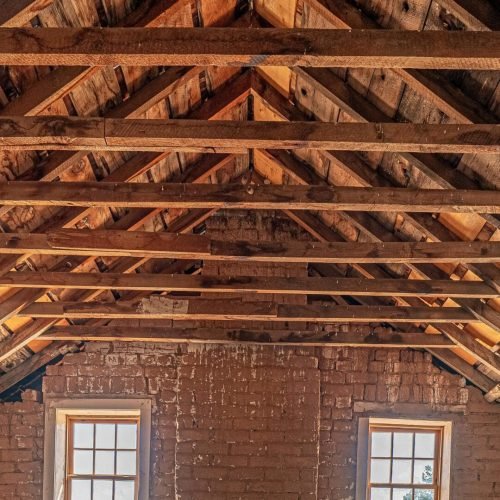 Spacious attic interior featuring exposed wooden beams and brick walls, perfect for renovation or design inspiration.